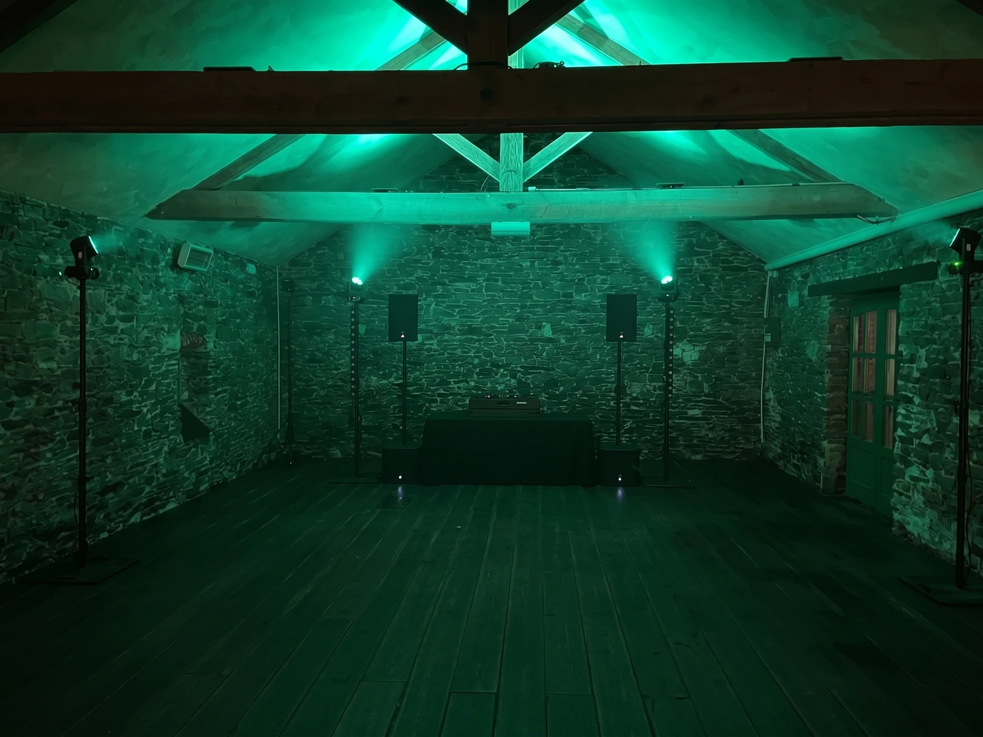 Installation Artha Évènementiel : enceintes, caissons, lyres, laser, barres LED et régie dans une salle éclairée en vert